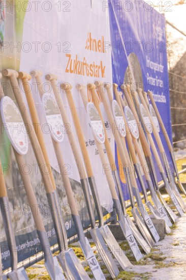 Row of spades standing in front of advertising banners on a sunny winter day on a building site, fiberglass groundbreaking, Freudenstadt, Germany