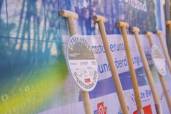 Row of shovels in front of an information poster at a symbolic event, fiberglass groundbreaking, Freudenstadt, Germany