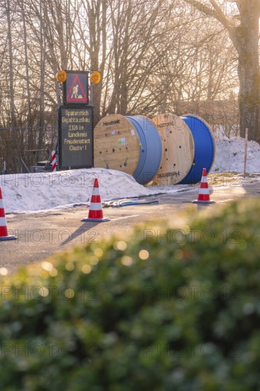 Cable drums and traffic cones on a construction site in the snow at sunrise, fibreglass groundbreaking, Freudenstadt, Germany