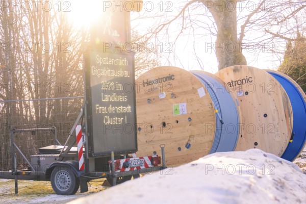 Two rolls of cable next to a glowing construction site sign in a winter environment, fibreglass groundbreaking, Freudenstadt, Germany