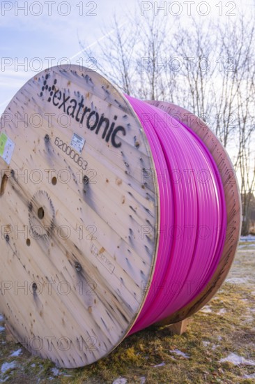 A large pink cable reel stands in a meadow under a blue sky in winter, fiberglass groundbreaking, Freudenstadt, Germany