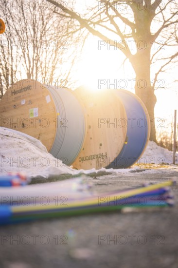 Cable rolls in sunset with snowy ground and bare trees in the background, fiberglass groundbreaking, Freudenstadt, Germany
