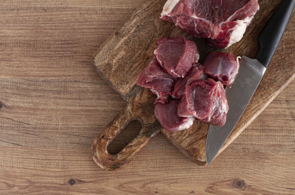 Raw beef meat, sliced on a cutting board, with a knife, no spices, no herbs, top view, wooden table, homemade, no people