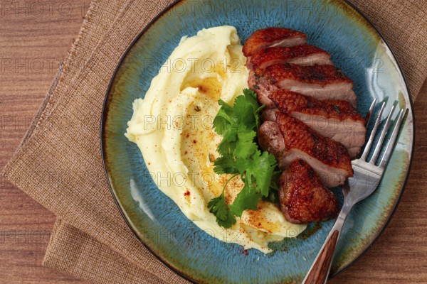 Roast duck breast, sliced with mashed potatoes, on a plate, close-up, no people