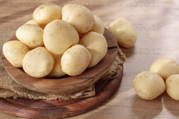 Boiled new potatoes, in a wooden bowl, on a rustic table, natural light, no people