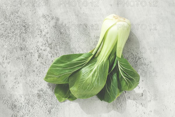 Fresh bok choy, laid out on a light gray surface, top view, natural light