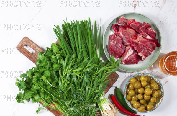 Ingredients for cooking chakapuli, canned tkemali, meat, herbs Georgian cuisine, top view