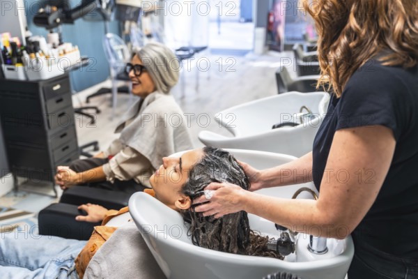 Hairstylist giving a customer a relaxing hair wash and massage at the shampoo station in a modern hair salon, providing beauty treatment and pampering experience