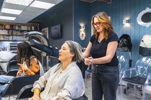 Professional hairdresser washing and styling a smiling mature womans gray hair in a modern salon, offering attentive hair care, pampering, and confident grooming service