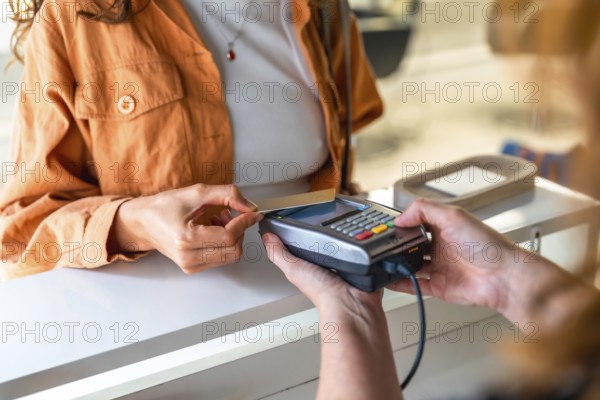 Woman tapping a contactless credit card on a pos terminal at a salon checkout, completing a cashless payment for services in a modern retail setting, close up on hand and card