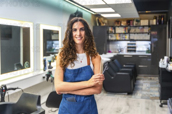 Woman hairstylist entrepreneur smiling, standing in a small business hair salon, holding hair scissors and a comb, symbolizing professionalism, expertise, and dedication to beauty and style