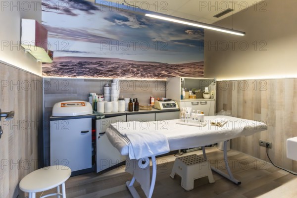 Professional beauty salon interior featuring a comfortable treatment bed, various skin care preparations, and modern aesthetic equipment, creating a serene environment for wellness