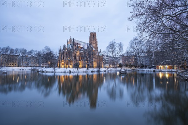 March 18, 2018, winter dusk with snow, illuminated lake and Gothic church Johanneskirche, calm reflections, Feuersee, Stuttgart, Baden-Württemberg, Germany