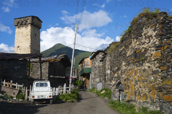 A village street with a white wagon, surrounded by stone buildings and power poles, defensive towers, Ushguli, Murqmeli district, Upper Svaneti, Svaneti, Georgia