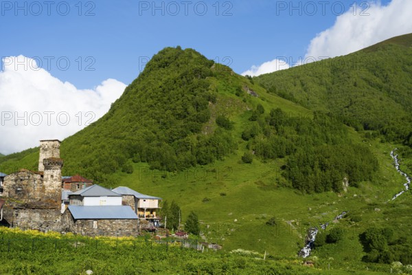A green mountain with stone houses under a cloudy sky, defensive towers, Ushguli, Ushguli, Murqmeli district, Upper Svaneti, Svaneti, Georgia