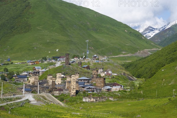 Mountain village with old stone towers surrounded by green hills and mountains under a partly cloudy sky, defensive towers, Ushguli, Ushguli, Chazhashi, Upper Svaneti, Svaneti, Georgia