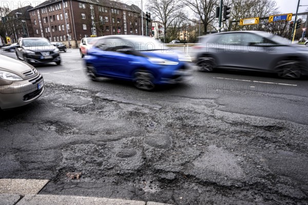 Large potholes at the confluence of Kruppstraße with Friedrichstraße, B224, heavy vehicle traffic, cars and trucks, as well as winter weather conditions have severely added to the road surface, Essen, North Rhine-Westphalia, Germany