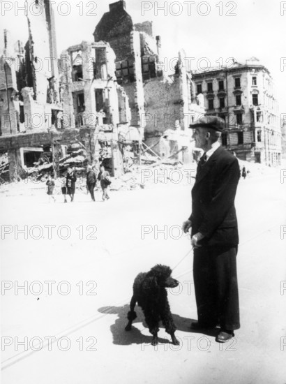 Civilians, man walking with dog (poodle) in the ruins of Berlin, June 1945, Berlin, Germany