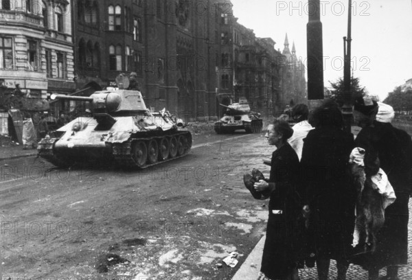 Soviet tanks at the Mehringdamm subway station, Landwehrkanal, civilians on the side of the road, Kreuzberg, Berlin 30.4.1945, Germany J. Chaldej about this photo: Our tanks rolled. It was April 30, 1945. Three woman came out of the subway. I was wearing a black coat, a black cap. A woman said, “What kind of tanks are they? 'I said: Soviet. “No, ” she said, “that can't be.”