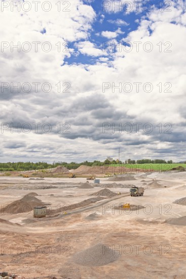 View of an open pit mine with truck and heavy machinery and gravel piles