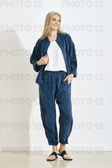 Smiling woman stands in a studio wearing a comfortable outfit, consisting of a matching jacket and pants
