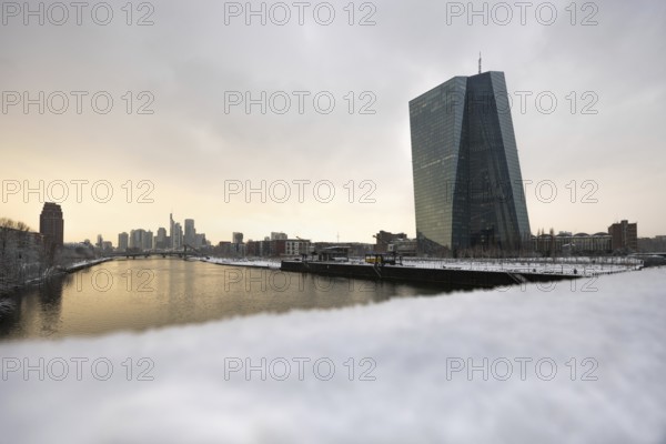 Snow lies along the banks of the Main from the European Central Bank (ECB) to the Frankfurt banking skyline, Osthafen, Frankfurt am Main, Hesse, Germany