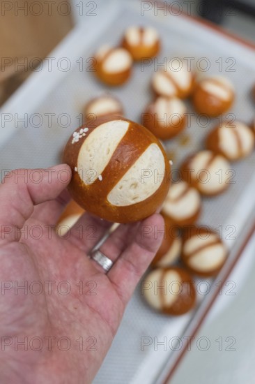 Simple pretzel held in hand with salt, more in the background, baking rolls, Haselstaller Hof, Gechingen, Germany