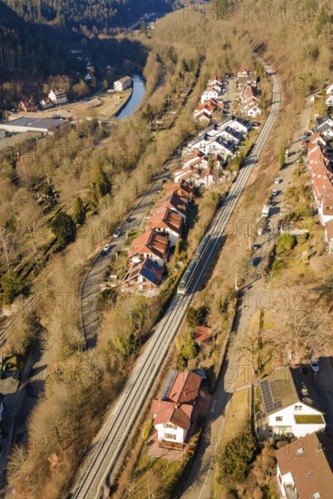 Aerial view of a village with railroad tracks, surrounded by forests and a river, test run on the new Hermann-Hesse railway with Siemens Mireo Plus B trains, Calw, Germany