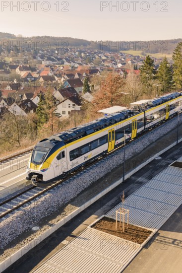 Modern train on rails near a settlement with typical roof houses and nature, test run on the new Hermann-Hesse railway with Siemens Mireo Plus B trains, Calw, Germany