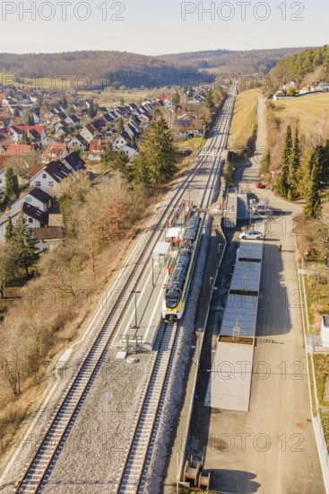 Zug travels on a railway line through a rural, densely built-up area with trees, test run on the new Hermann-Hesse railway with Siemens Mireo Plus B trains, Calw, Germany