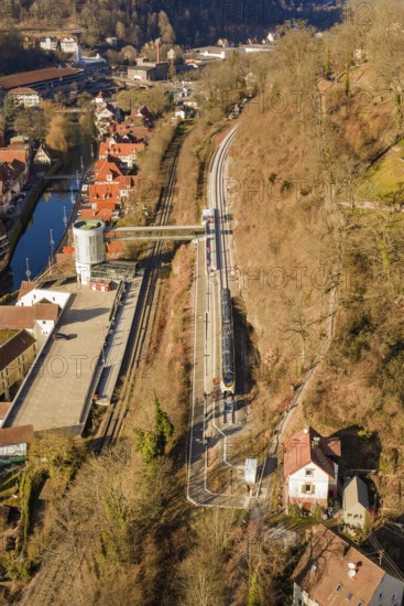 Train travels through a hilly landscape with village and river from a bird's eye view, test trip on the new Hermann-Hesse railway with Siemens Mireo Plus B trains, Calw, Germany