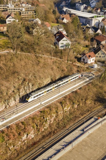 Train travels through a village on elevated tracks surrounded by hills and houses, test run on the new Hermann-Hesse railway with Siemens Mireo Plus B trains, Calw, Germany