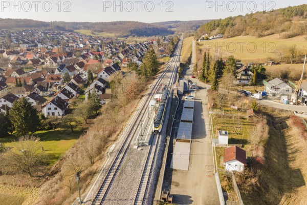 Railway line runs through a village with red-roofed houses, surrounded by trees and meadows, test run on the new Hermann Hesse railway with Siemens Mireo Plus B trains, Calw, Germany