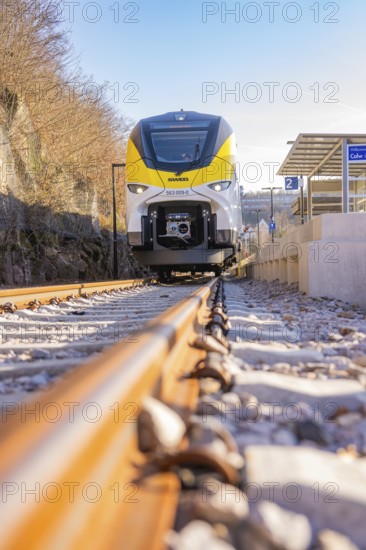 Close-up of a yellow and white train on gravel tracks at a bus stop, test run on the new Hermann-Hesse railway with Siemens Mireo Plus B trains, Calw, Germany