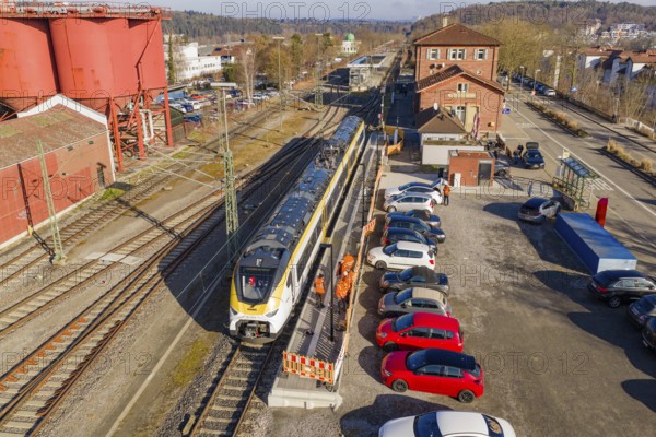 Train stands at a train station next to parked cars and industrial buildings, several workers in orange vests, test run on the new Hermann Hesse railway with Siemens Mireo Plus B trains, Calw, Germany