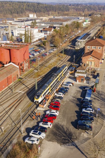 Train in a train station with adjacent parking lot and buildings in an industrial area, test run on the new Hermann-Hesse railway with Siemens Mireo Plus B trains, Calw, Germany