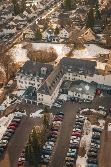A large building with an adjacent parking lot and a few snow-covered cars, district office, Freudenstadt, Black Forest, Germany