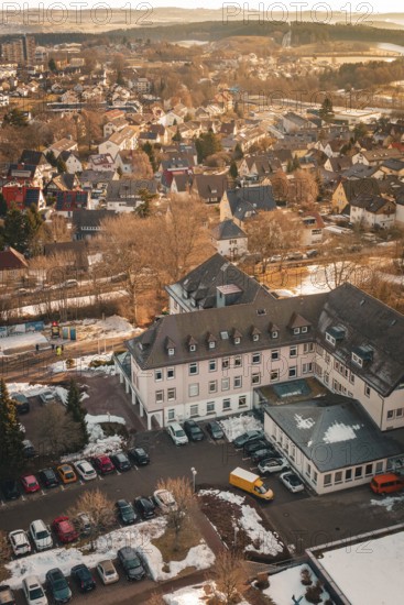 Urban scenery in winter with snow-covered houses and cloudless sky in warm lighting, District Office, Freudenstadt, Black Forest, Germany
