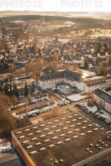 Urban area in winter with snow-covered houses and roads in warm sunlight from a bird's eye view, District Office, Freudenstadt, Black Forest, Germany
