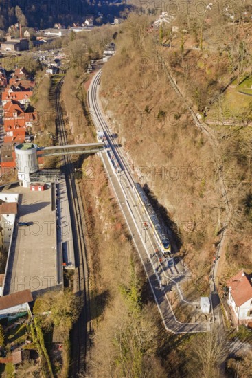 Aerial view of a railway line along a wooded slope with urban surroundings, test run on the new Hermann-Hesse railway with Siemens Mireo Plus B trains, Calw, Germany