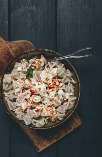 The dish features a generous serving of Turkish dumplings topped with velvety yogurt and a drizzle of spicy red sauce