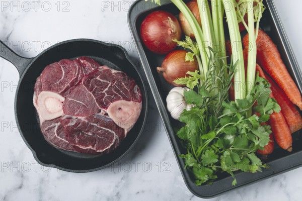 Sknuckle on the bone, raw meat for ossobuco, in a cast-iron pan, baking sheet with vegetables, top view, no people