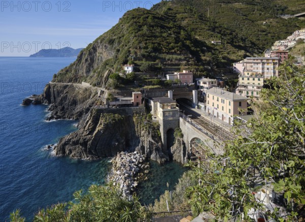 Coastal landscape with houses and view of the train station in the fishing village of Riomaggiore, Cinque Terre, La Spezia province, Liguria, Italy