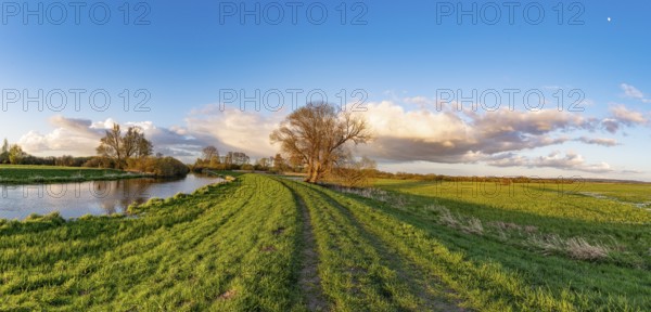 The Hunte river near its mouth in Dümmer See, landscape with river and meadow path under blue sky and clouds, Dümmet nature park Park, Lower Saxony, Germany