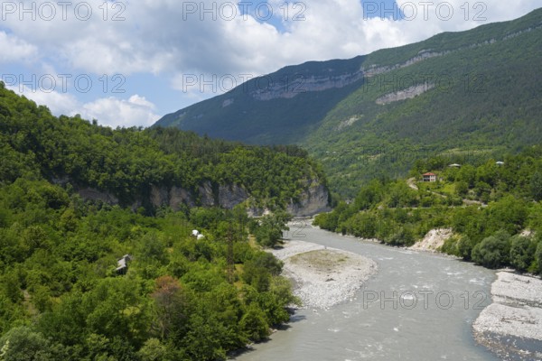 River flows through a wooded valley in the mountains under a cloudy sky, Rioni river near Alpana, Racha-Lechkhumi region and Lower Svaneti, Georgia