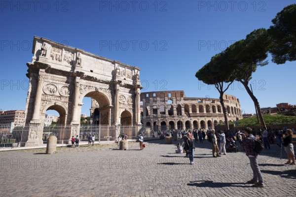 Arch of Constantine and Colosseum surrounded by tourists under blue sky, Rome, Lazio, Italy