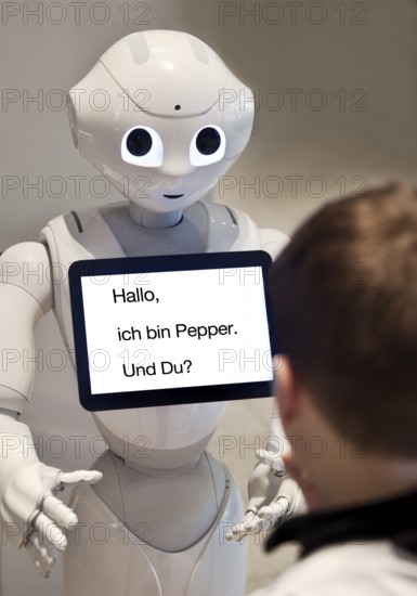 Pepper, a humanoid robot with a tablet and a boy in dialogue, artificial intelligence, AI, Germany