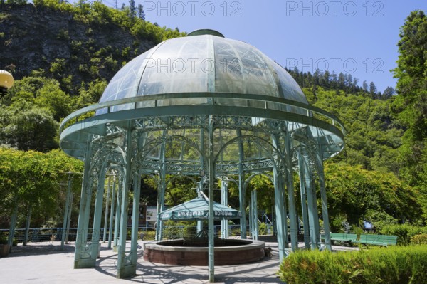Metal glass pavilion surrounded by a green garden under clear summer sky, pavilion with mineral water spring, Borjomi Park, Borjomi, Borjomi resort, Borjomi, Samtskhe-Javakheti region, Samtskhe-Javakheti, Lesser Caucasus, Georgia