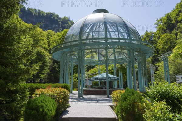 An elegant glass and metal pavilion in a green, sunny landscape surrounded by trees, pavilion with mineral water spring, Borjomi, Borjomi, Borjomi resort, Borjomi, Samtskhe-Javakheti region, Samtskhe-Javakheti, Lesser Caucasus, Georgia