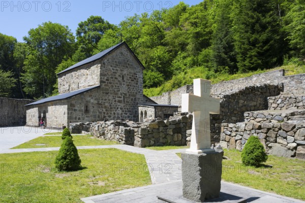 Stone cross in front of a historic church surrounded by green nature, Chitakhevi Church of St. George, The Green Monastery, Mtsvane Monastery, Samtskhe-Javakheti Region, Samtskhe-Javakheti, Georgia
